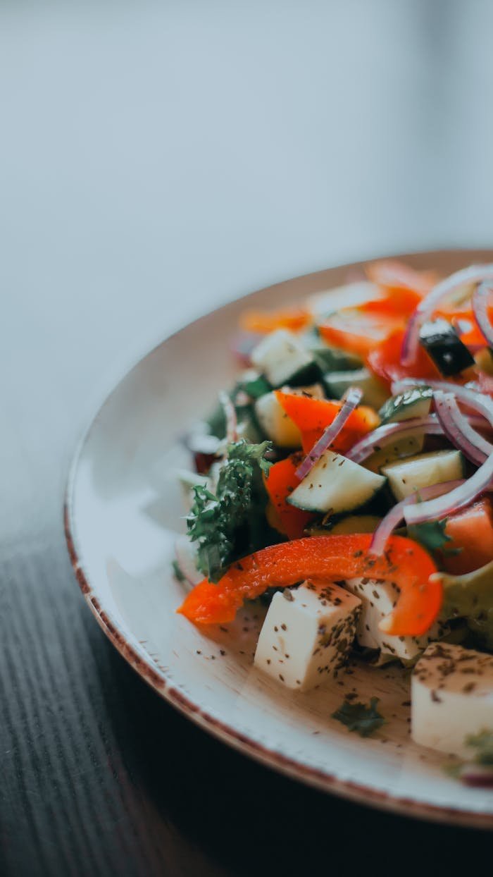Contact Colorful vegetable salad with feta cheese and herbs on a ceramic plate, ideal for healthy eating concepts.