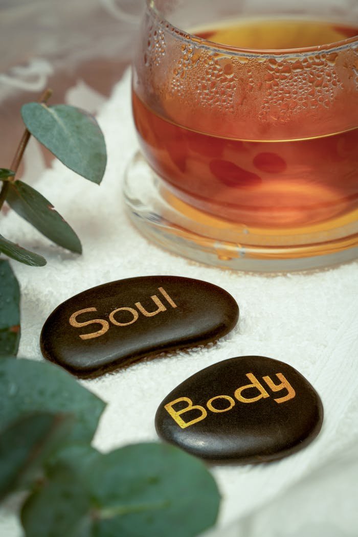 Calming spa scene with eucalyptus leaves, tea, and engraved stones for relaxation.