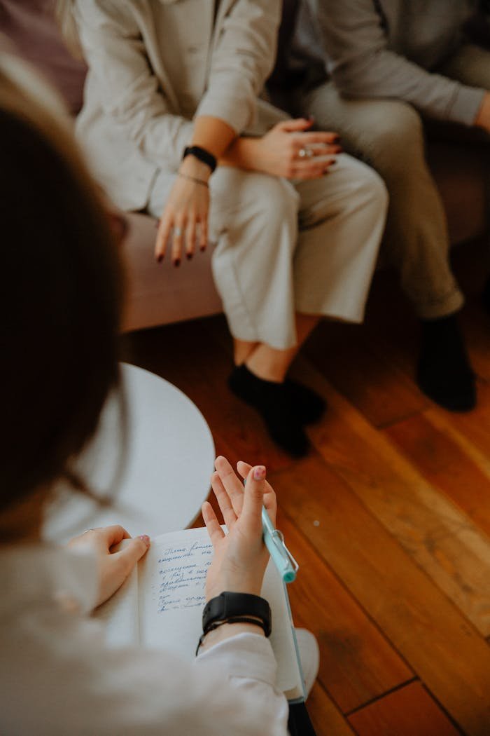 The Art of Drawing Readers In: Your attractive post title goes here A therapy session with a counselor taking notes while clients discuss issues on a couch.