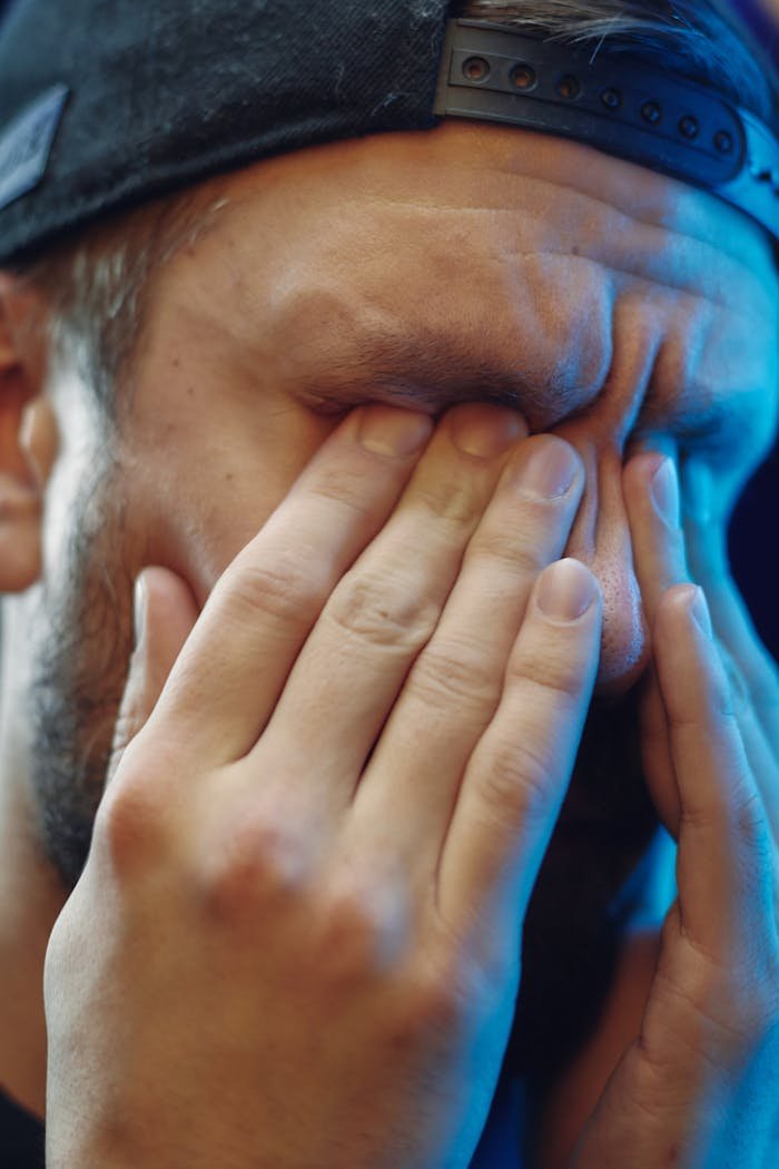 About Close-up of a man rubbing his eyes, portraying stress or fatigue. Emotional expression in focus.